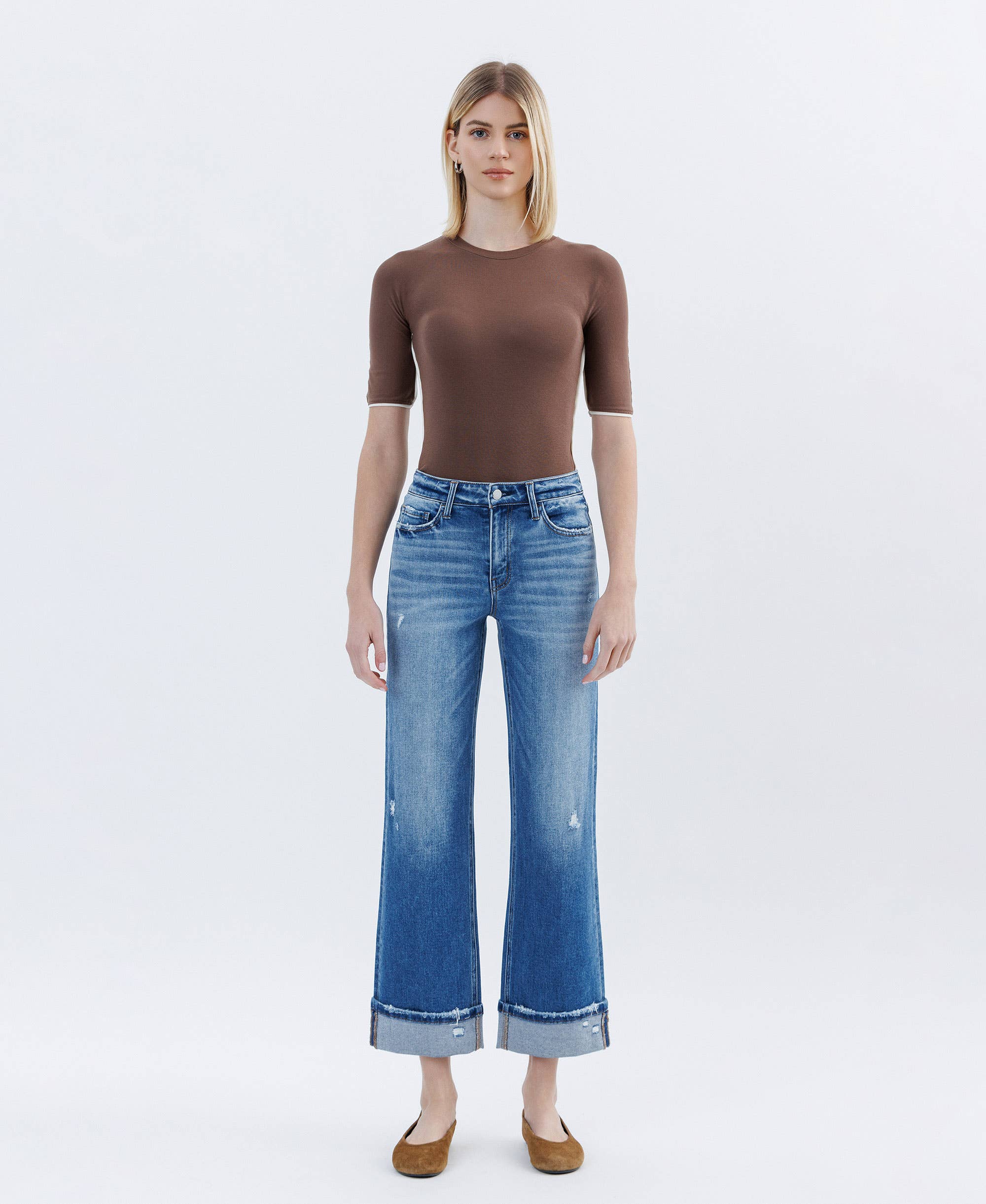 Slim wide leg high rise cuffed jeans in distressed blue denim worn by model