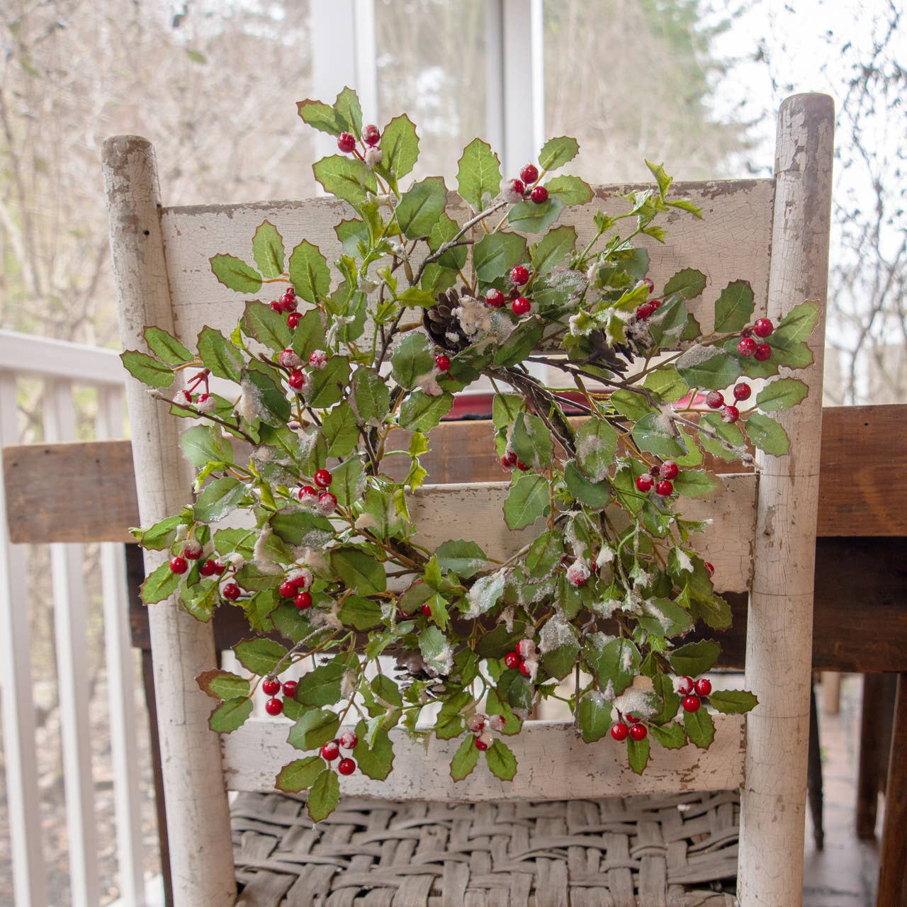 15-inch glittered holly berry and pinecone wreath Christmas decoration on rustic chair