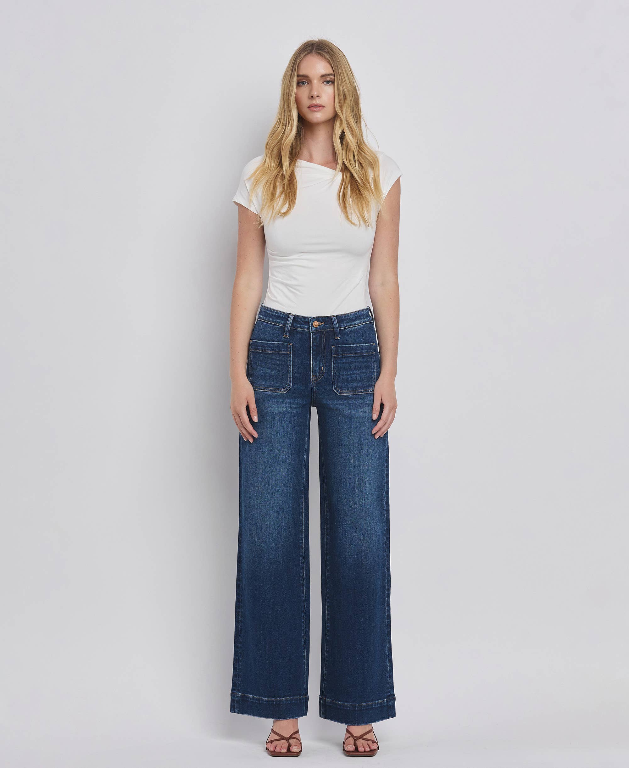 Woman wearing high rise wide leg jeans with patched pockets and full-length comfort stretch denim