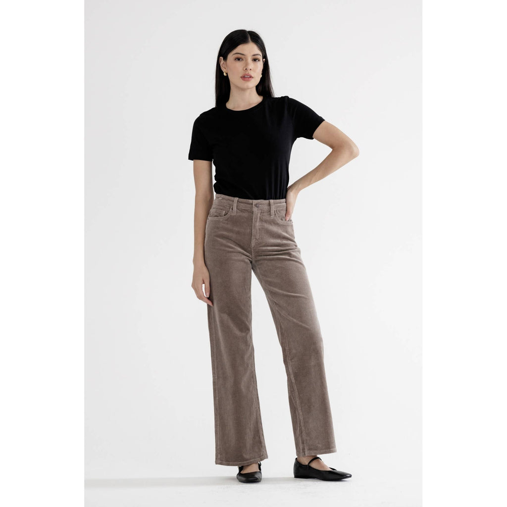 Woman wearing light greige high rise wide leg pants with black top and black shoes against white background